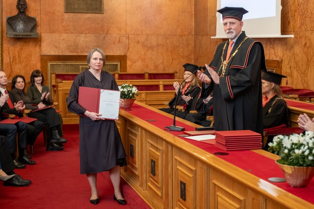 Marjeta Kramar Fijavž ob prejemu priznanja v dvorani UL. Poleg rektor, v ozadju občinstvo.