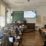 kupina mednarodne poletne šole PLANNED: Rivers and Routes: Rethinking and Enhancing Belgrade’s Blue-Green Infrastructure pred tablo v učilnici predstavlja rezultate dela. Ostali udeleženci sedijo v klopeh, pred seboj imajo računalnike.